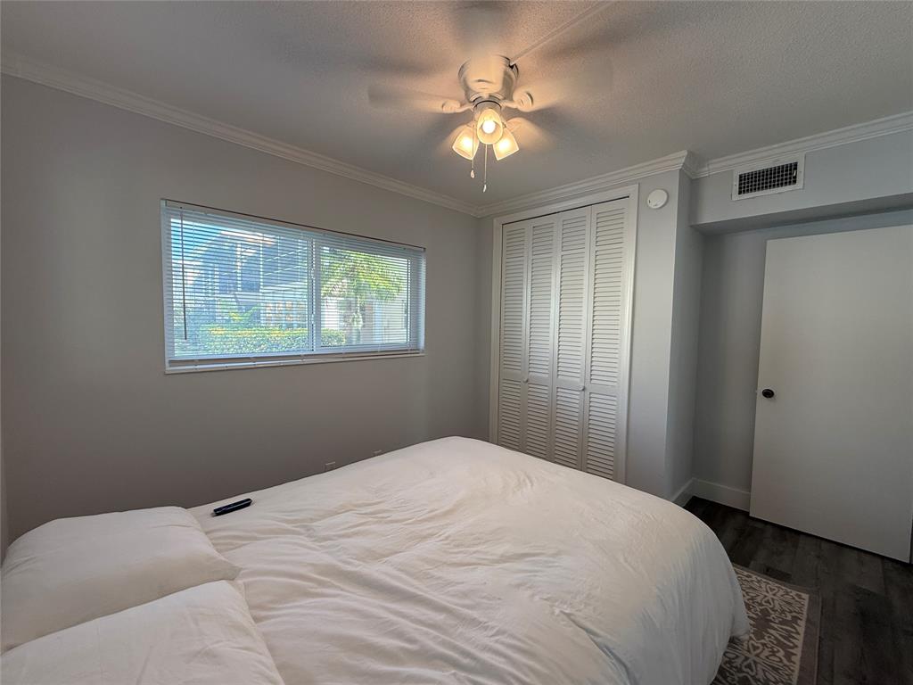 2121 Northeast 42nd Court, Unit 103C Lighthouse Point, FL 33064 - Photo 20 of 31 a bedroom with a bed and a chandelier