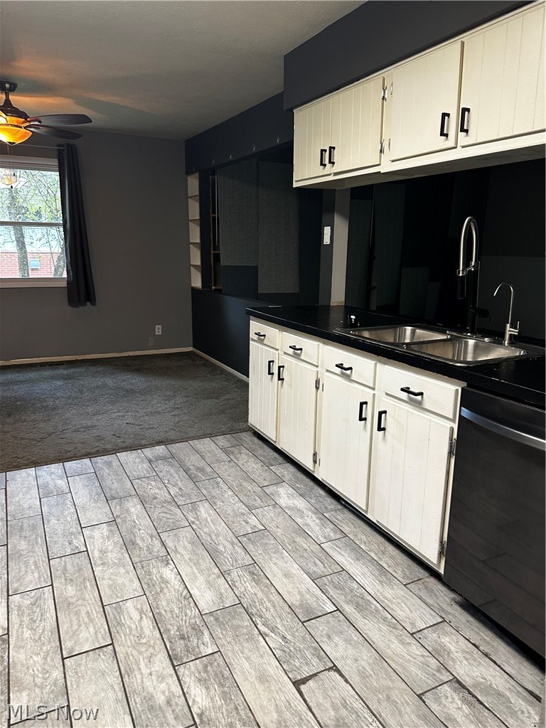 198 Park Road Painesville, OH 44077 - Photo 10 of 31 Kitchen area featuring wood-finish tile flooring, white cabinetry with black hardware, a double basin sink, and black countertops