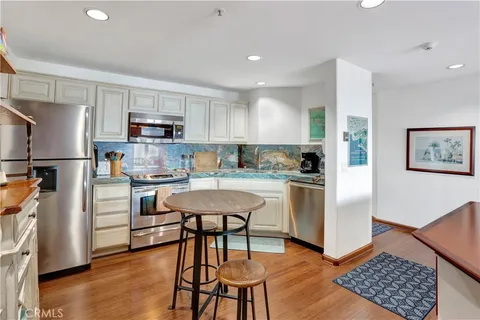 a kitchen with stainless steel appliances a refrigerator a stove a sink dishwasher and a refrigerator with wooden floor