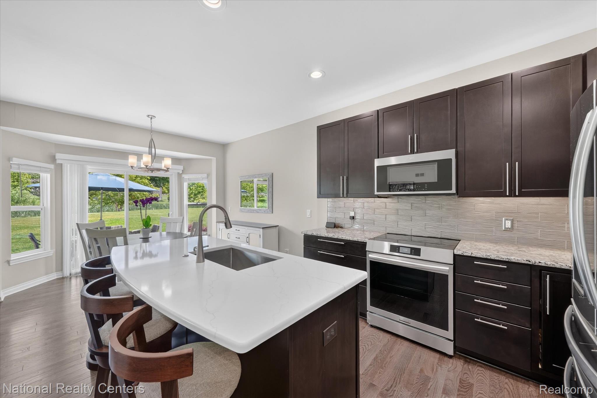 740 North Mill Street South Lyon, MI 48178 - Photo 18 of 56 Modern kitchen with a white countertop island featuring an undermount sink and a gooseneck faucet