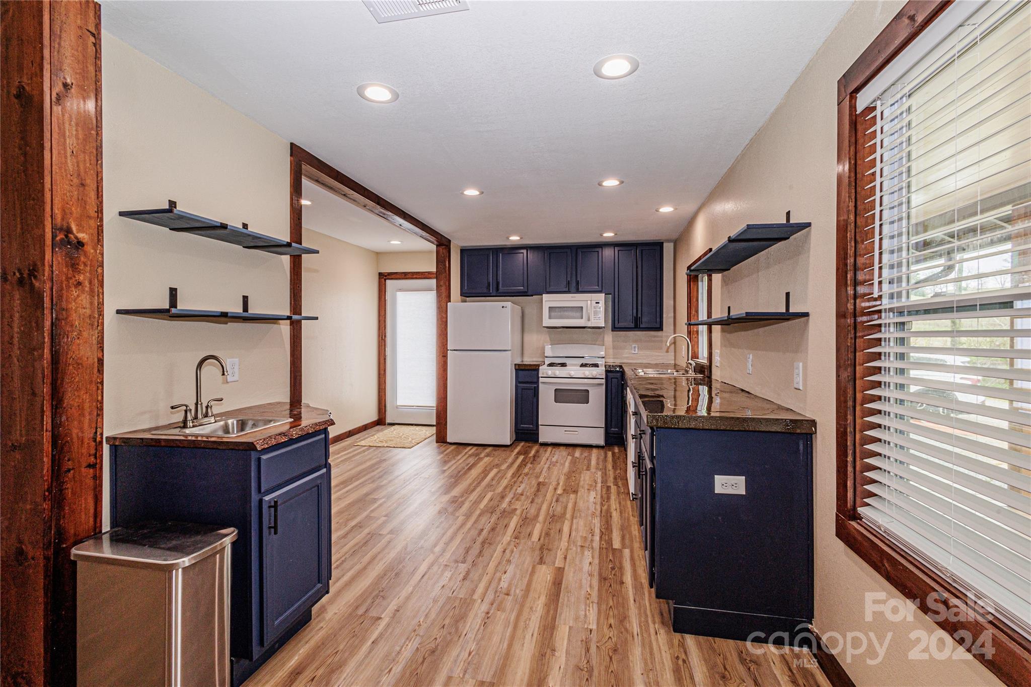1233 Bryson Branch Road Bryson City, NC 28713 - Photo 6 of 28 a kitchen with stainless steel appliances granite countertop a refrigerator a sink dishwasher a stove and white countertops with wooden floor