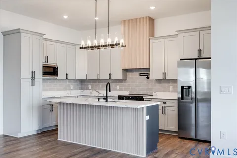 a kitchen with stainless steel appliances granite countertop a sink a refrigerator a center island a stove and cabinets