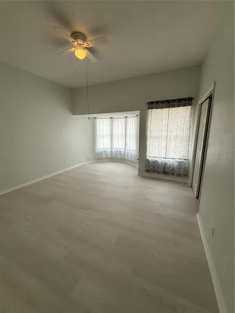 an empty room with windows and fan