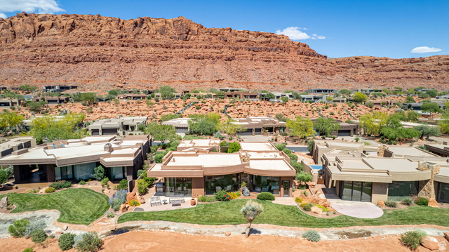 2331 West Entrada Trail, Unit 61 St. George, UT 84770 - Photo 66 of 69 Desert modern architecture featuring an expansive green lawn, mature landscaping, and red rock mountain backdrop
