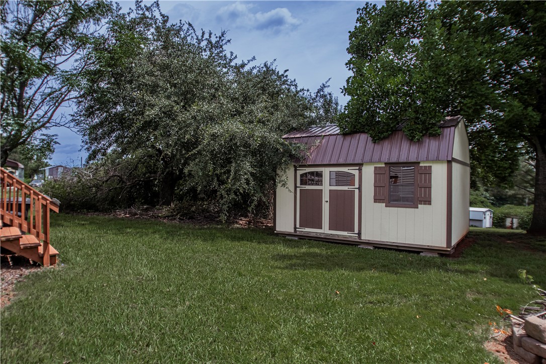 169 West Bagwell Road Liberty, SC 29657 - Photo 7 of 29 A quaint storage shed with a metal roof nestled within a verdant yard, offering practical outdoor utility.