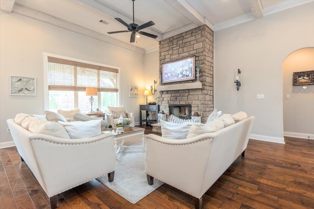 608 Cypress Run Cove Collierville, TN 38017 - Photo 8 of 40 Living area with dark wood-style floors, ceiling fan, beamed ceiling, arched walkways, and a fireplace