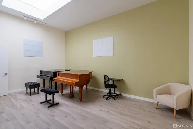 a room with furniture wall paintings a piano and a window