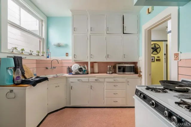 a kitchen with stainless steel appliances granite countertop a stove a sink and a granite counter tops with white cabinets next to a window