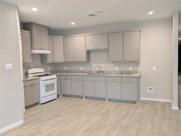 a kitchen with granite countertop a sink stainless steel appliances and cabinets