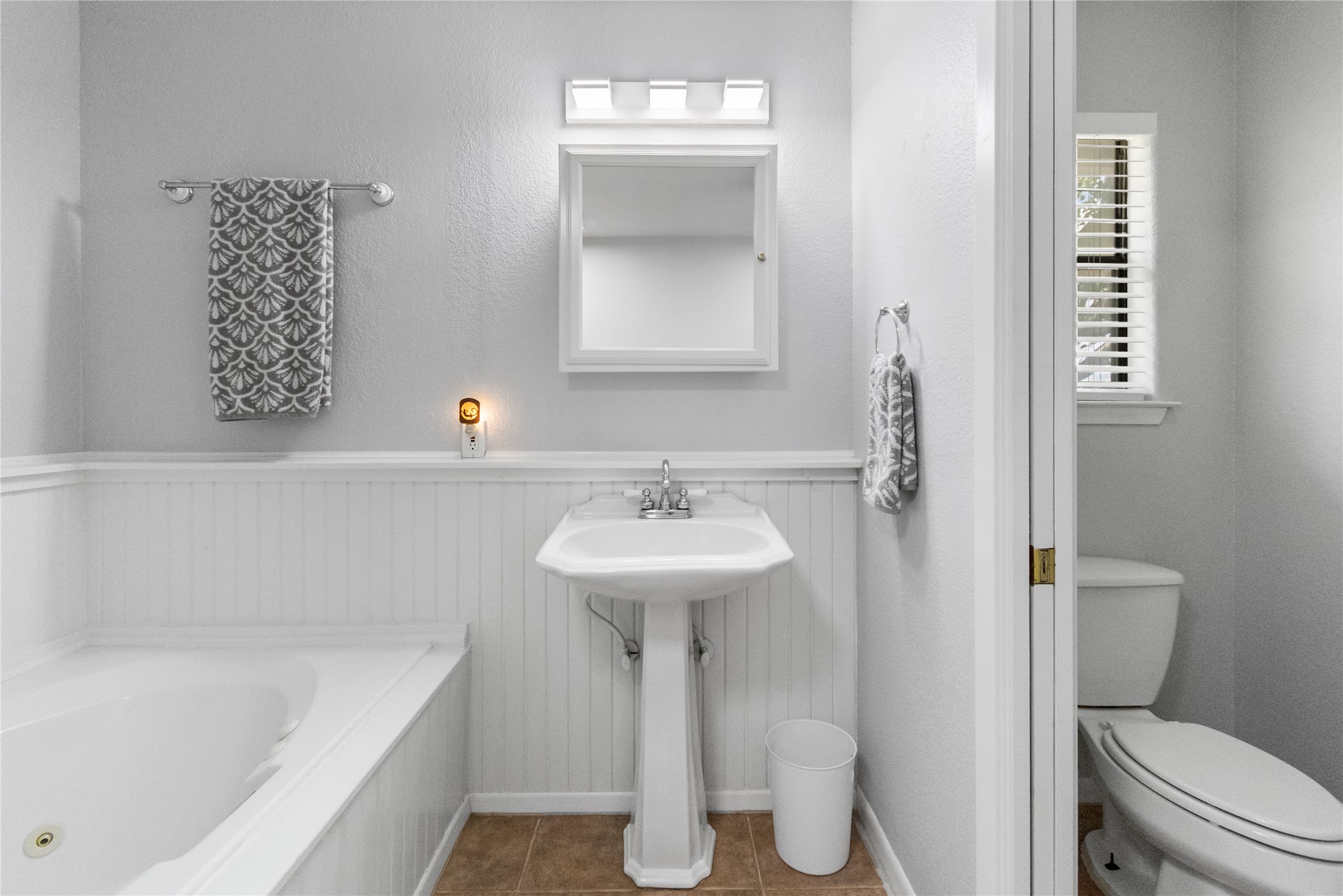 210 Teeoff, Unit B Horseshoe Bay, TX 78657 - Photo 23 of 38 A well-appointed bathroom features a classic pedestal sink, a deep soaking tub, and tile flooring for comfortable living.