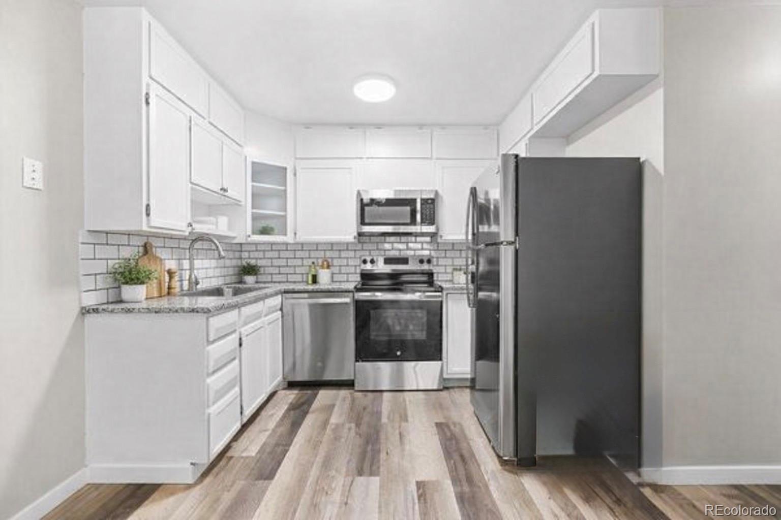 9335 Center Avenue, Unit 1B Denver, CO 80247 - Photo 2 of 15 a kitchen with granite countertop a refrigerator stove top oven and sink