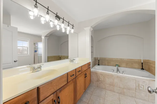 a spacious bathroom with a granite countertop sink a large mirror and a bathtub