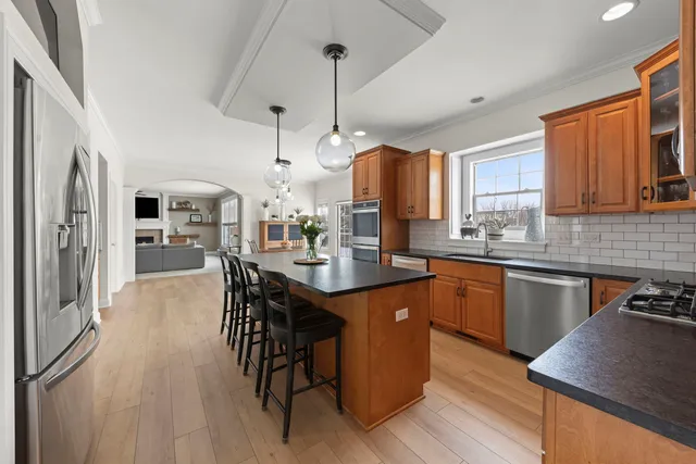 a kitchen with stainless steel appliances granite countertop a sink a stove a refrigerator cabinets and dining table