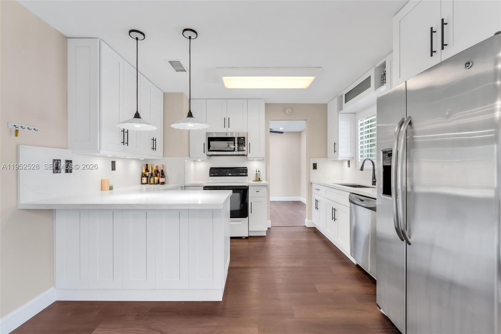 9567 Southwest 59th Terrace Miami, FL 33173 - Photo 12 of 36 a kitchen with white cabinets and stainless steel appliances