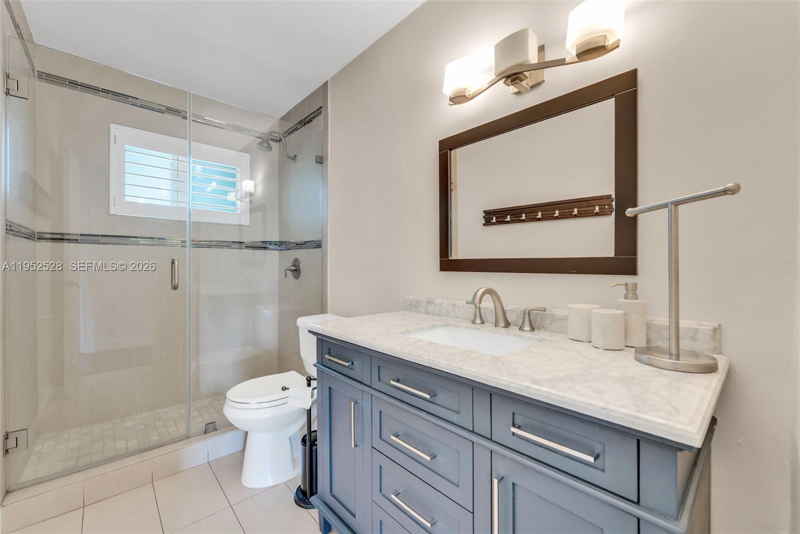 9567 Southwest 59th Terrace Miami, FL 33173 - Photo 17 of 36 a bathroom with a granite countertop sink a toilet and a mirror