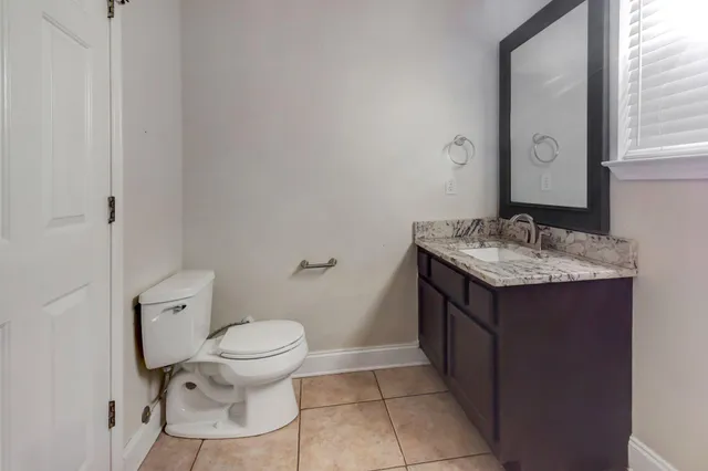 a bathroom with a granite countertop sink a toilet and a mirror