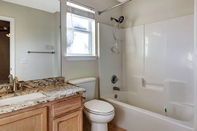 a bathroom with a granite countertop toilet a sink and a bathtub