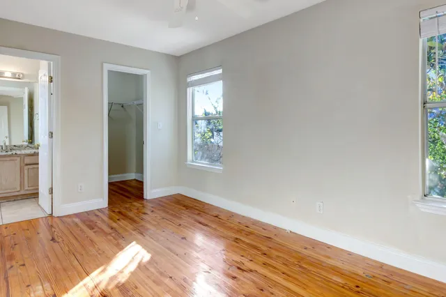 an empty room with wooden floor and windows
