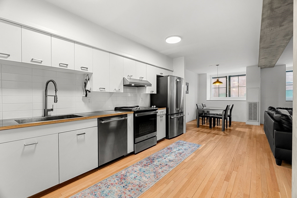 200 Market Street, Unit 103 Lowell, MA 01852 - Photo 1 of 22 a kitchen with stainless steel appliances granite countertop a refrigerator a sink dishwasher a stove and white countertops with wooden floor