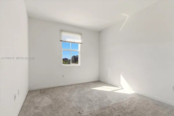 a view of an empty room with furniture and window