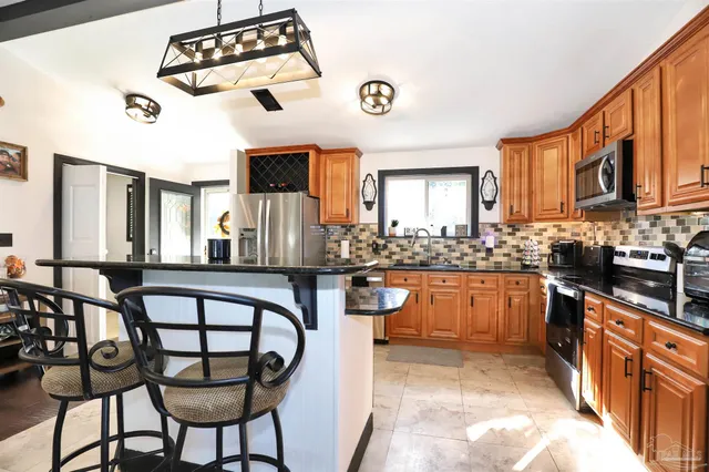 a kitchen with stainless steel appliances granite countertop a stove top oven a sink a dining table and chairs with wooden floor