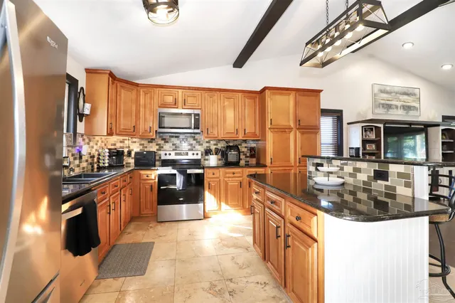 a kitchen with stainless steel appliances granite countertop a stove a sink dishwasher and a refrigerator