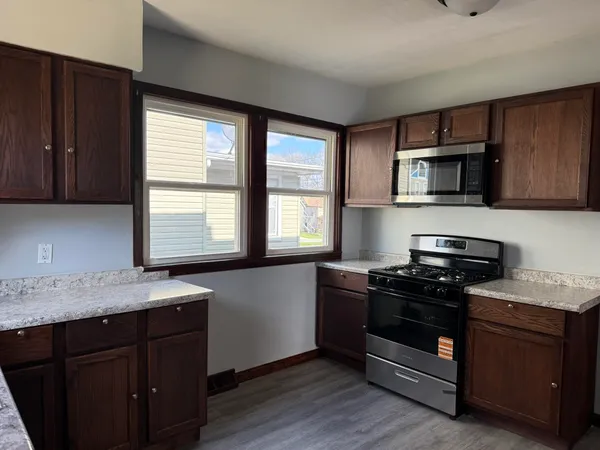 a kitchen with granite countertop wooden cabinets stove top oven and sink