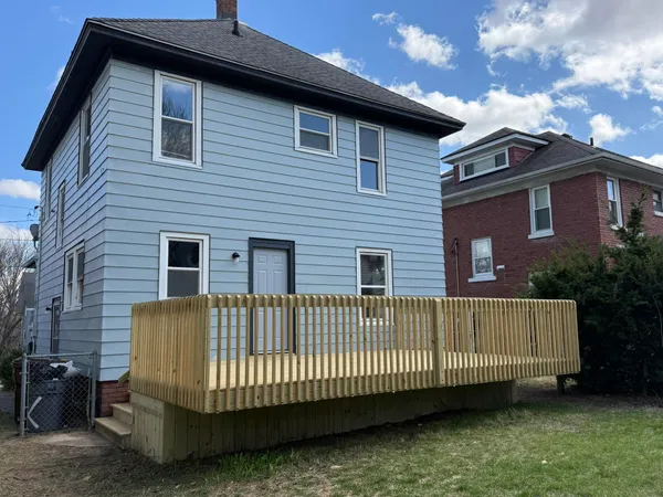 a view of a house with a small yard and wooden fence