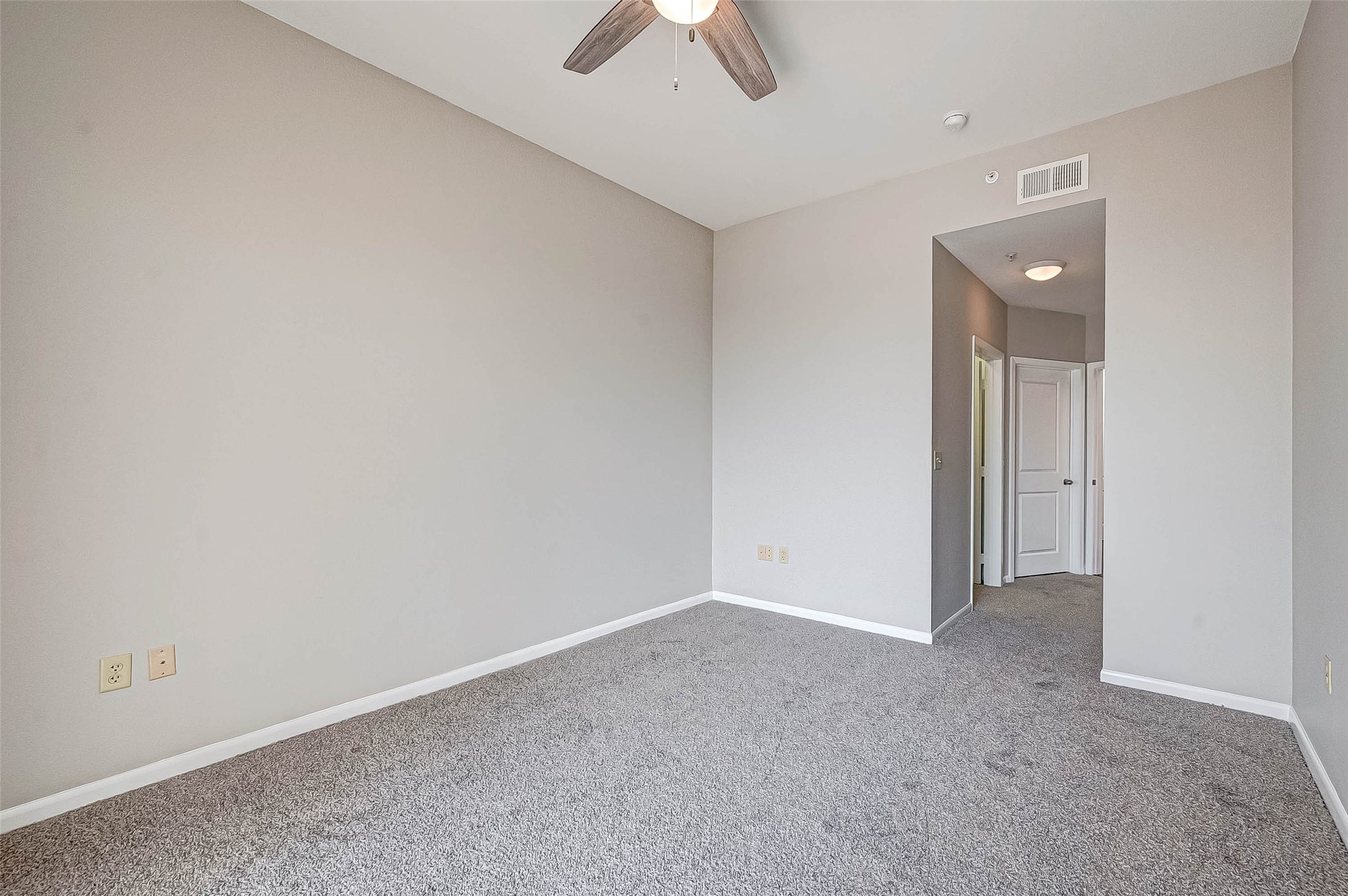 3505 Sage Road, Unit 2106 Houston, TX 77056 - Photo 14 of 31 This room features soft gray walls, carpeted flooring, and a ceiling fan. It has an open entrance leading to a hallway with doors, providing a clean and modern look.