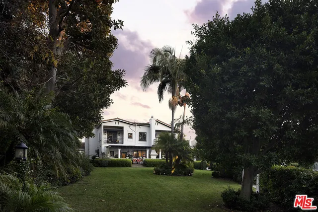 a view of a white house with a big yard and large trees