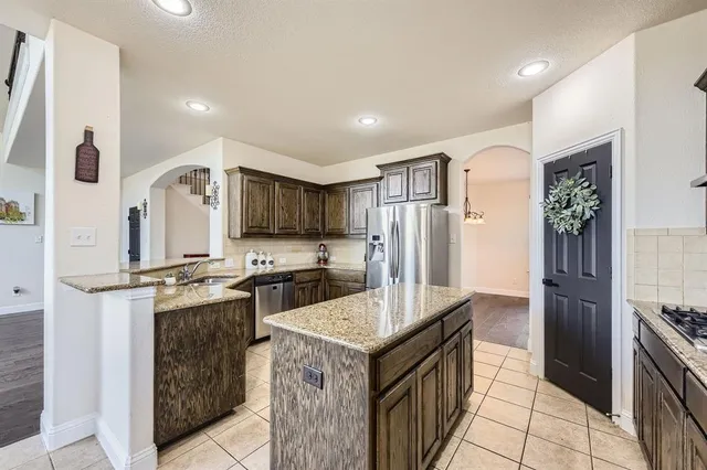 a kitchen with stainless steel appliances granite countertop a refrigerator a stove and a sink