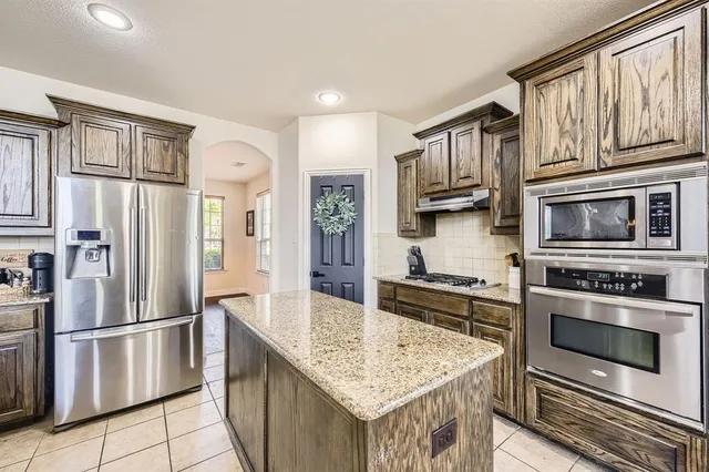 a kitchen with stainless steel appliances granite countertop a refrigerator stove top oven and sink