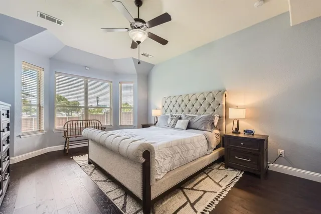 a bedroom with a large bed and a chandelier fan