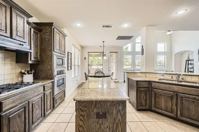 a kitchen with kitchen island granite countertop a sink stove and refrigerator