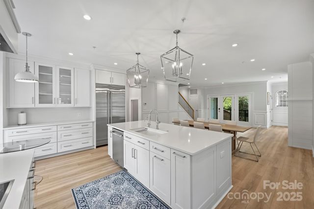 a large white kitchen with a large island oven a stove a sink a dining table and chairs