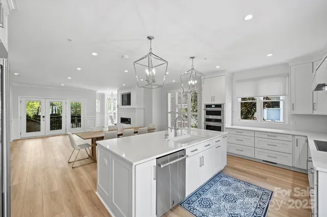 a large white kitchen with a large window a sink and stainless steel appliances