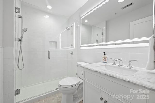 a bathroom with a granite countertop sink a toilet and shower