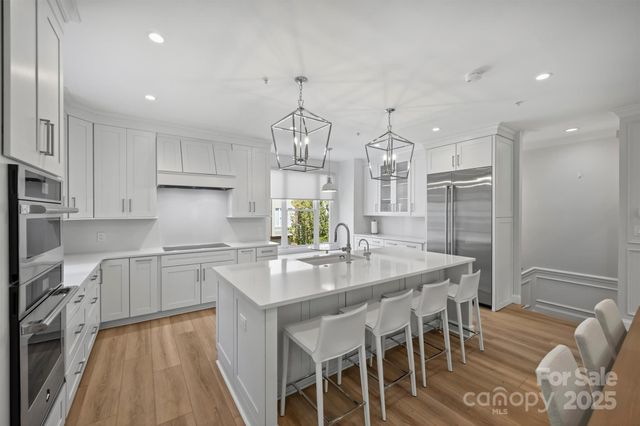 a kitchen with stainless steel appliances granite countertop a kitchen island a stove a table and chairs in it