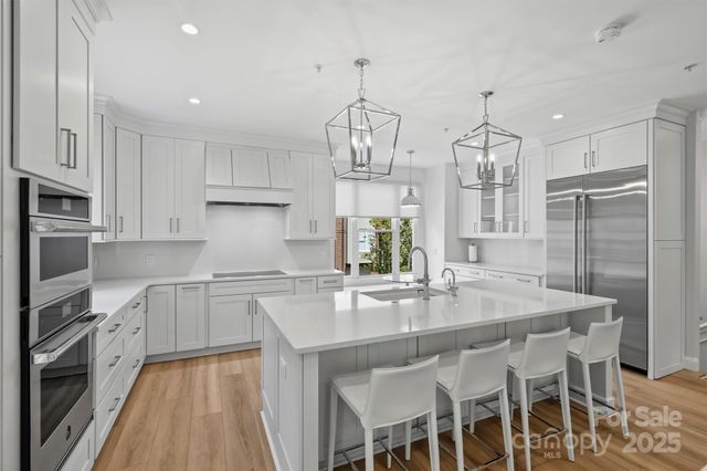 a kitchen with stainless steel appliances granite countertop a kitchen island a stove a table and chairs in it