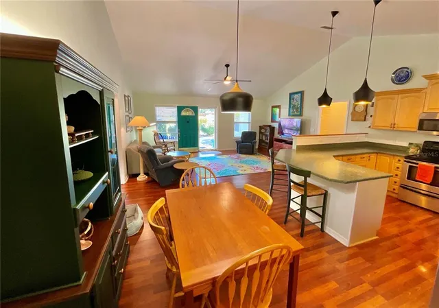 a kitchen with stainless steel appliances granite countertop a stove a refrigerator a dining table and chairs with wooden floor