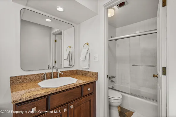 a bathroom with a granite countertop sink toilet and shower