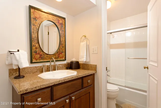 a bathroom with a granite countertop sink a toilet and a mirror