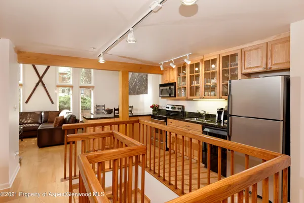 a kitchen with stainless steel appliances granite countertop a refrigerator a sink dishwasher a stove and a dining table with wooden floor