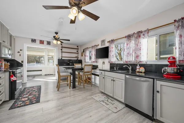 a kitchen with stainless steel appliances granite countertop a stove top oven a sink a dining table and chairs with wooden floor