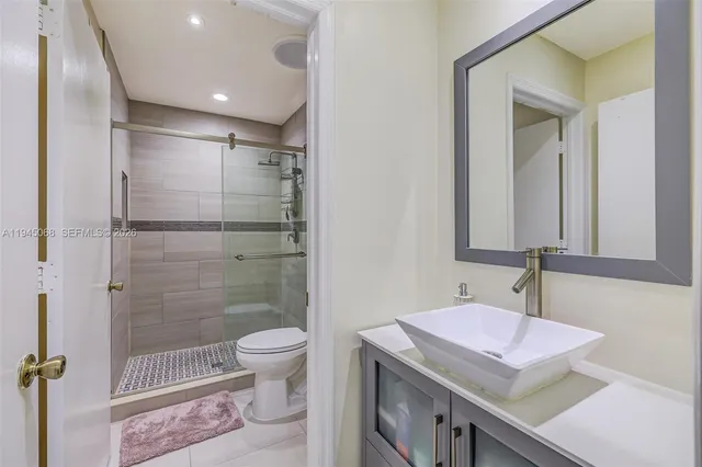 a bathroom with a granite countertop sink a toilet a mirror and shower