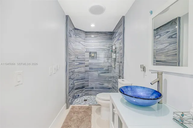 a bathroom with a granite countertop sink a toilet and a mirror