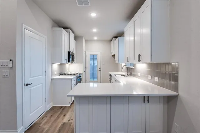 a kitchen with kitchen island white cabinets and stainless steel appliances