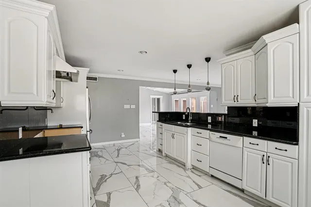a kitchen with granite countertop a sink a stove and cabinets