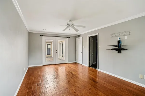 a view of empty room with wooden floor and fan