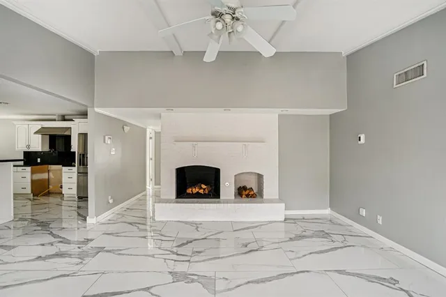 a view of an empty room with a fireplace and chandelier fan